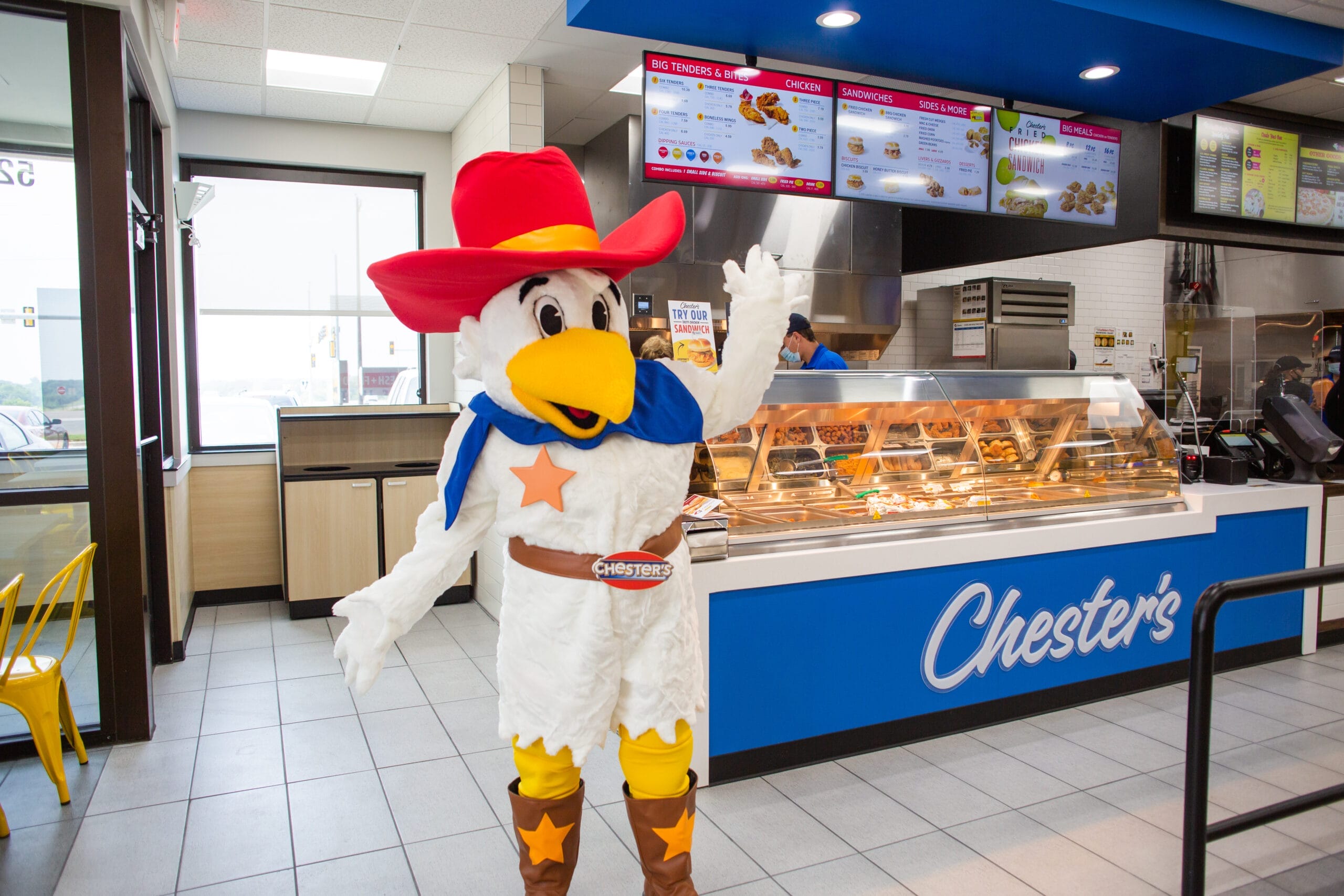 Fresh fried chicken being served inside a modern convenience store food counter with hot grab-and-go meals and customer traffic
